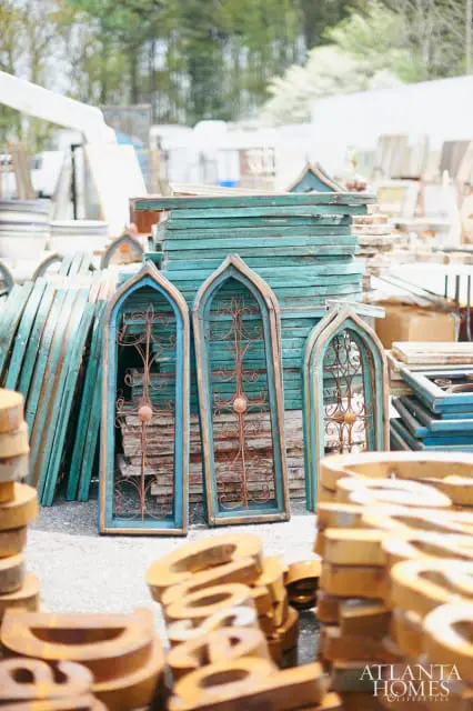Stacked teal architectural salvage windows with ornate metal inserts and weathered wooden frames.