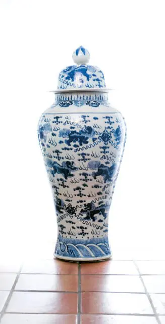 Blue and white porcelain ginger jar with foo dog and cloud motifs, on a tiled surface.