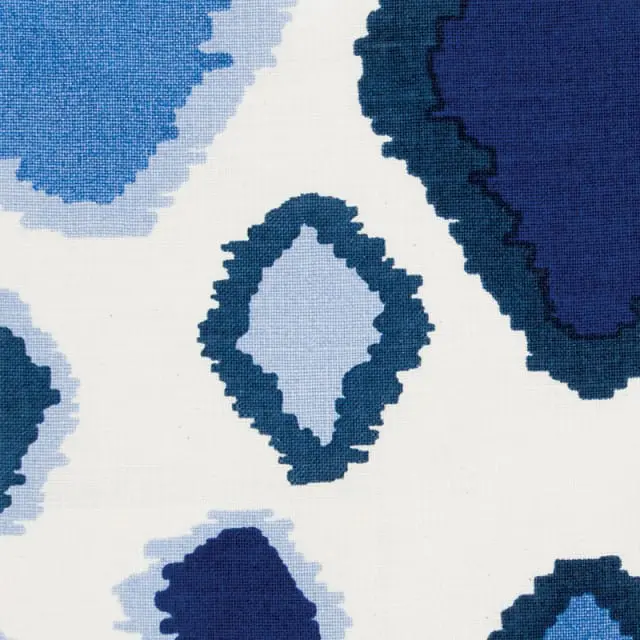 Close-up of a white fabric with a repeating abstract pattern in various shades of blue, including navy, royal blue, and light blue.
