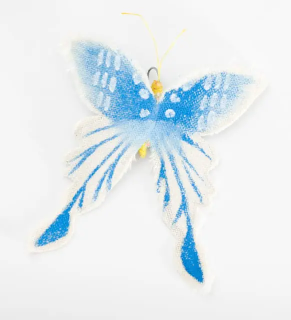 Blue and white fabric butterfly decoration with frayed edges and yellow antennae