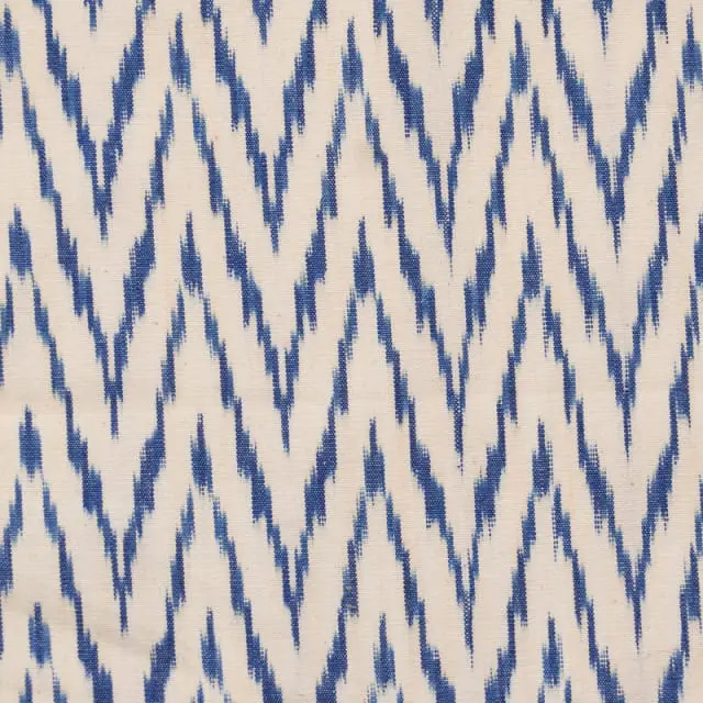 Close-up of a cream-colored fabric with a repeating pattern of jagged blue lines forming a chevron design.