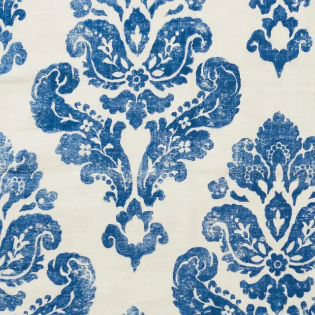 Close-up of a white fabric with a distressed blue damask pattern.