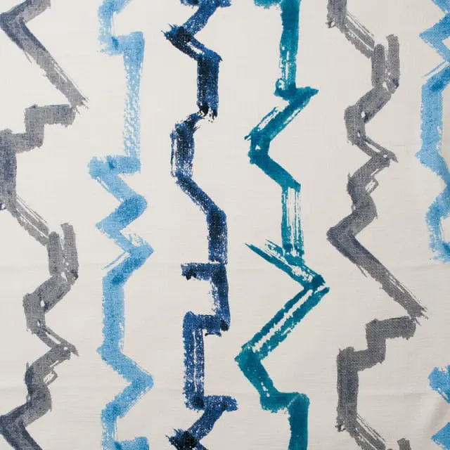 Close-up of a textured fabric with a repeating abstract pattern of jagged lines in shades of blue, teal, and gray.