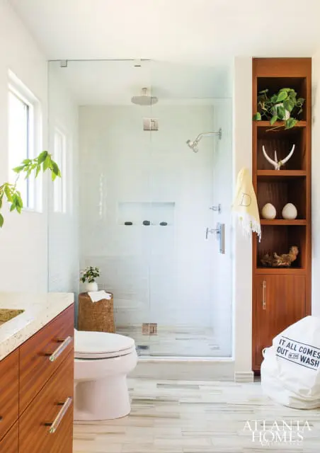 Modern bathroom with glass-enclosed shower featuring white subway tile, wood vanity with granite countertop, and built-in wood shelving.
