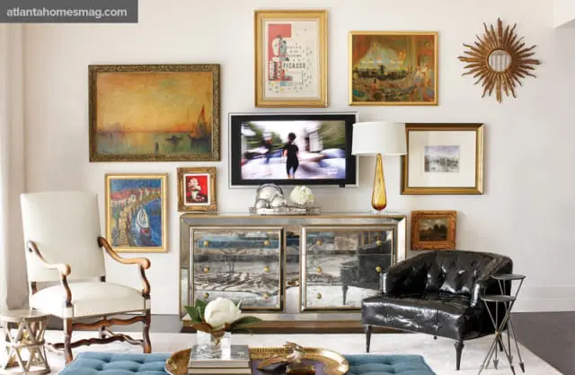 Living room with a mirrored dresser, tufted black leather armchair, and a collection of framed art on the wall above a flat-screen TV.
