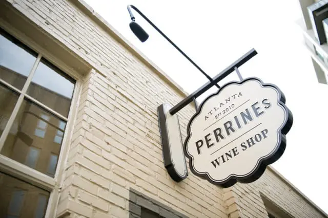 Perrines Wine Shop sign with "Atlanta Est 2010" above "Perrines Wine Shop" text, mounted on a cream brick building.