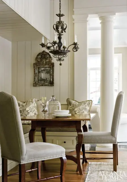 Dining nook with paneled walls, a dark wood table, upholstered chairs, and a wrought iron chandelier.