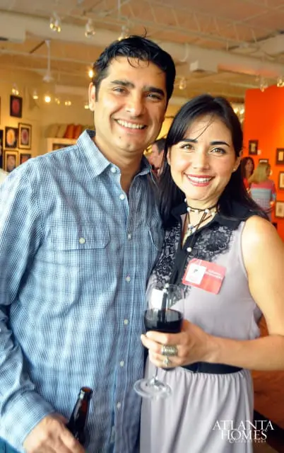 Man in blue plaid shirt and woman in lavender dress smiling, woman holds wine glass and wears name tag that reads "Adriana Hernandez"