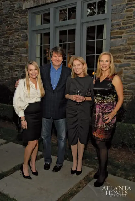 Four people standing in front of a stone building with large windows. The two women on the left and right are smiling, while the two people in the center are looking forward. The Atlanta Homes & Lifestyles logo is visible in the bottom right corner.