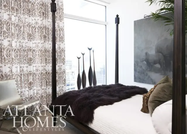 Bedroom with a dark wood four-poster bed, white quilted duvet, dark fur throw, and a large painting of rhinos above the bed.