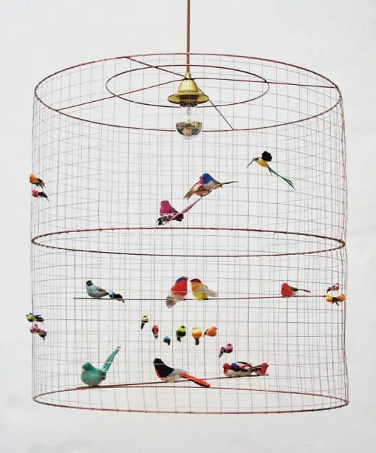 Wire birdcage-shaped pendant light with numerous decorative birds perched inside and on its exterior.