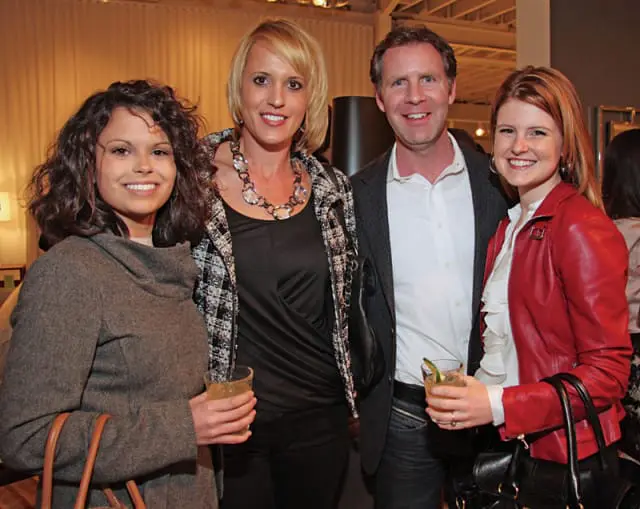 Four people posing indoors with cocktails.