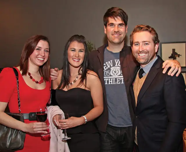 Two women and two men posing for a photo, with the women on the left wearing red and black dresses and the men on the right wearing jackets and t-shirts.