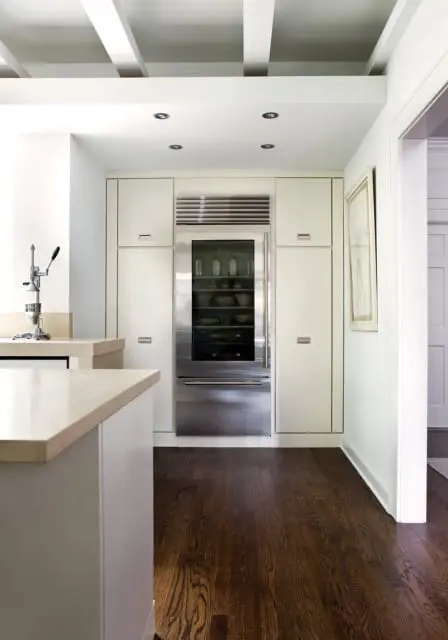 Modern kitchen with cream cabinetry, stainless steel refrigerator, and dark hardwood floors. White coffered ceiling with recessed lighting.