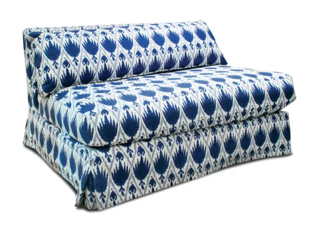 Armless sofa with blue and white ikat pattern upholstery, featuring a stacked cushion design and a skirted base.