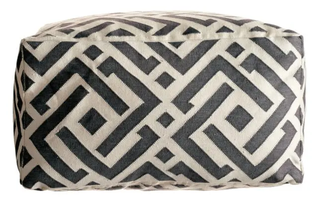 Close-up of a cube-shaped ottoman with a geometric pattern in charcoal gray and cream fabric.