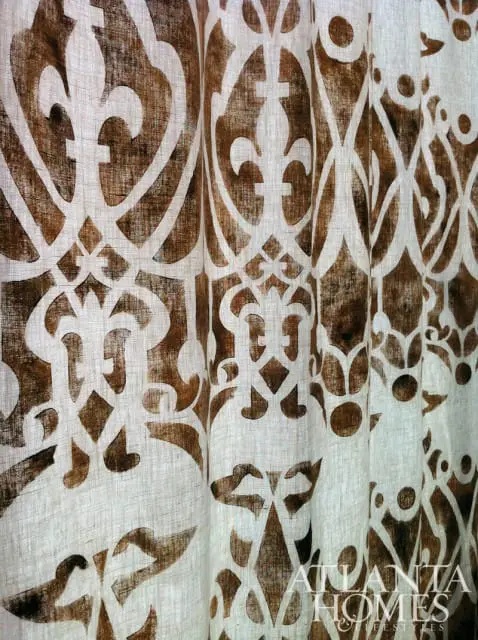 Close-up of a linen curtain with a repeating brown damask pattern. The Atlanta Homes & Lifestyles logo is visible in the lower right corner.