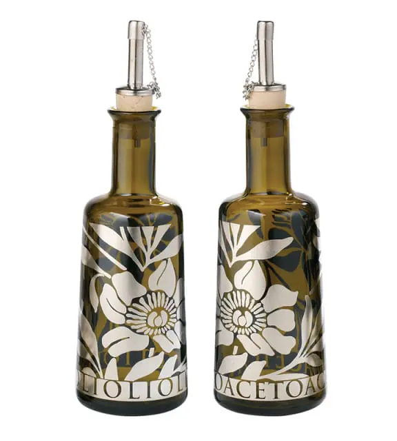 Two amber glass bottles with silver floral designs and metal pour spouts, one labeled 'OLIO OLIO' and the other 'ACETO AC'.