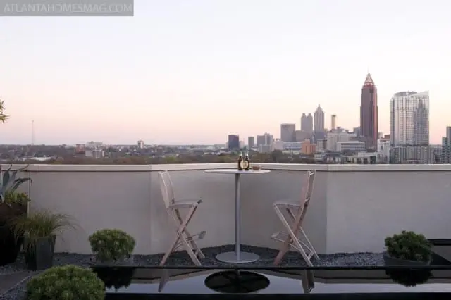 Rooftop patio overlooking Atlanta skyline at dusk, with a small table, two chairs, and a water feature in the foreground.