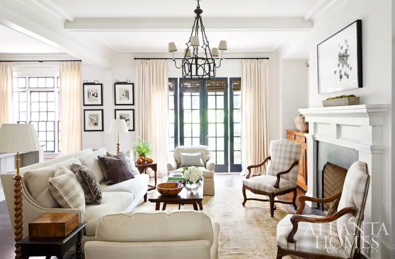 Living room with a white sofa, plaid armchairs, a white fireplace, and large French doors leading outside.