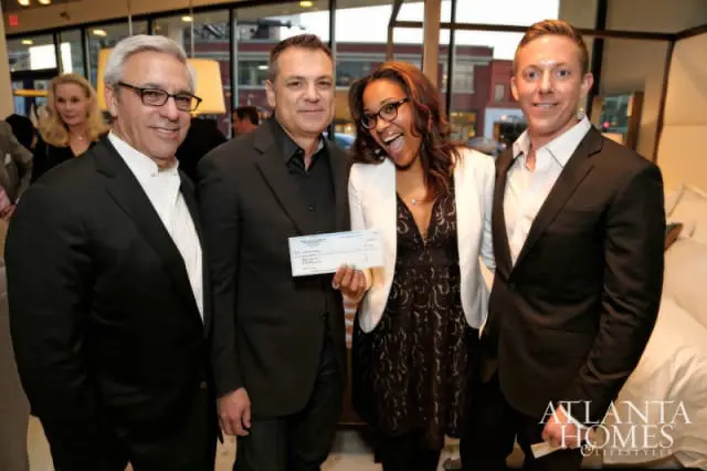 Four people pose for a photo, with one man holding a check. A logo for Atlanta Homes & Lifestyles is visible in the lower right corner.