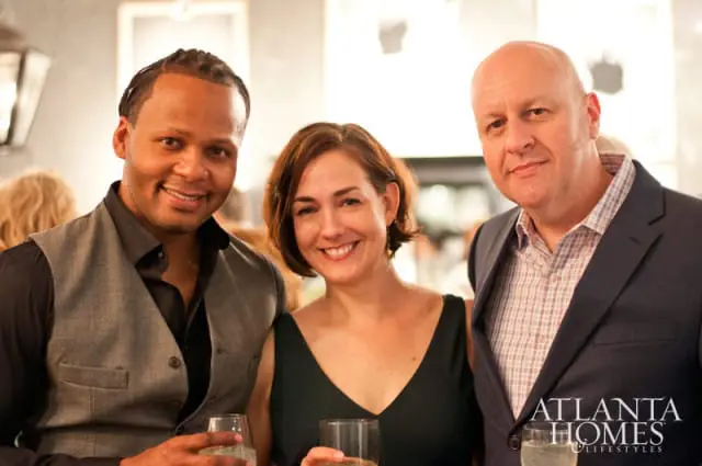 Three people smiling and holding drinks. The Atlanta Homes & Lifestyles logo is visible in the lower right corner.