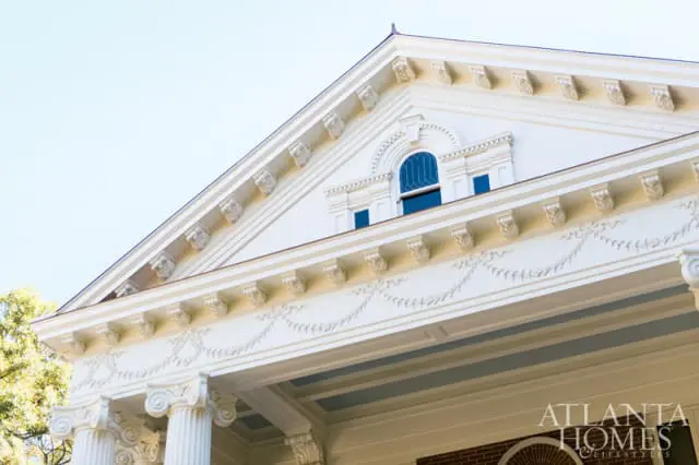 Classical white house exterior with ornate trim, columns, and arched window under a clear sky. Atlanta Homes & Lifestyles logo visible.