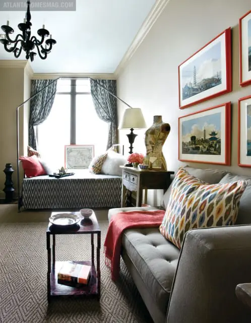 Living room with a gray tufted sofa, patterned throw pillows, a window seat with patterned cushions, and framed artwork of Asian pagodas on the wall.