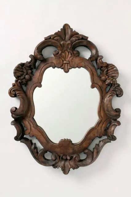 Ornate dark wood mirror frame with carved acanthus leaves, scrolls, and shell motifs in Rococo style.