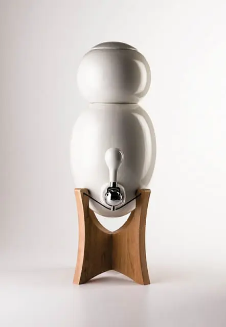 White ceramic water filter dispenser with chrome spigot on a wooden stand
