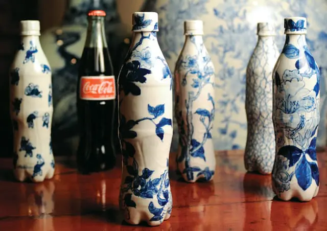 Coca-Cola bottle next to several plastic bottles decorated with blue and white Chinoiserie patterns.