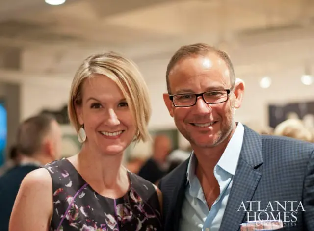 Paige Smith and Richardson smiling at the camera. Richardson wears glasses and a blue checkered suit jacket. Smith wears a floral dress.