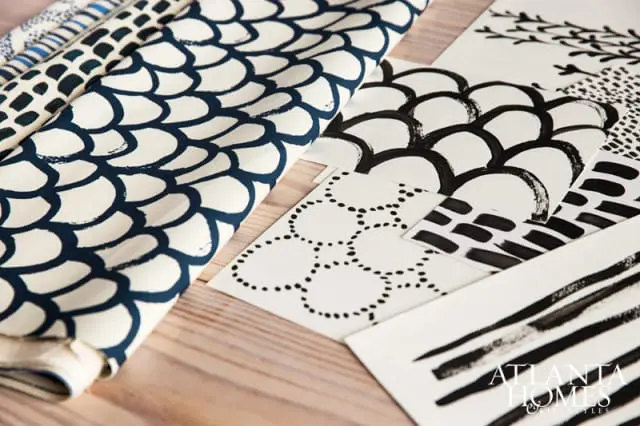 Fabric swatch with navy blue scale pattern next to papers with black ink abstract designs and Atlanta Homes & Lifestyles logo