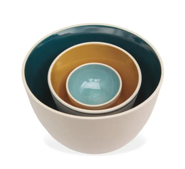 Set of three nesting ceramic bowls in cream, mustard yellow, teal, and light blue with a swirled pattern on the smallest bowl.
