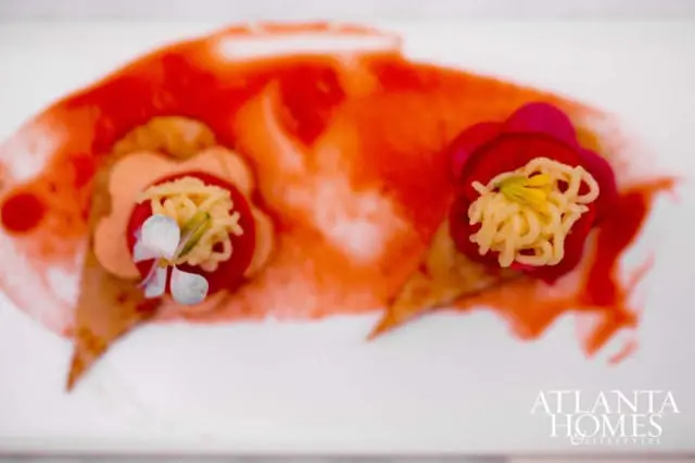 Two appetizers with crispy noodles and edible flowers on a white plate with a red sauce