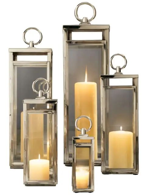 Set of five silver metal lanterns with glass panes and cream pillar candles, varying in height.