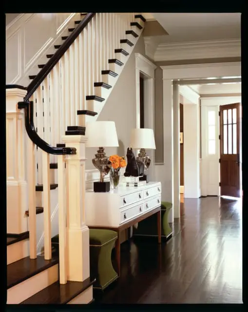 Entryway with dark wood floors, a white console table with two lamps, and a staircase with dark wood banister.