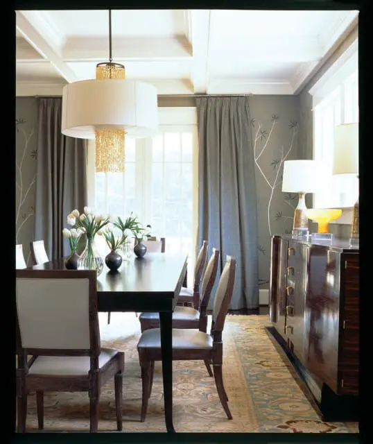 Dining room with dark wood table and chairs, white tulips in vases, a buffet, and a large drum pendant light with crystal accents.