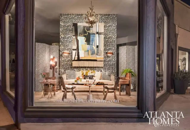 Living room vignette with a patterned wallpaper, abstract art, sofa, two chairs, and a glass-top coffee table.