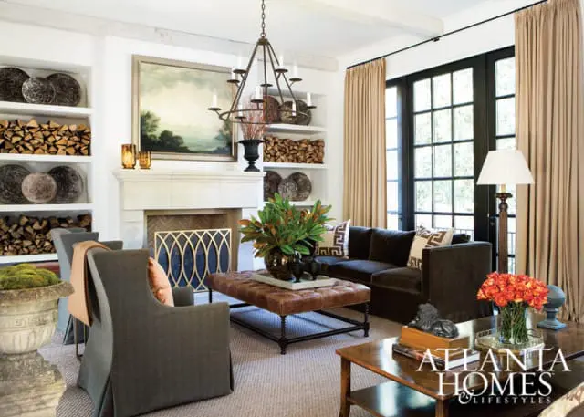 Atlanta Homes & Lifestyles magazine cover featuring a living room with a dark sofa, tufted leather ottoman, stone fireplace, and large French doors.