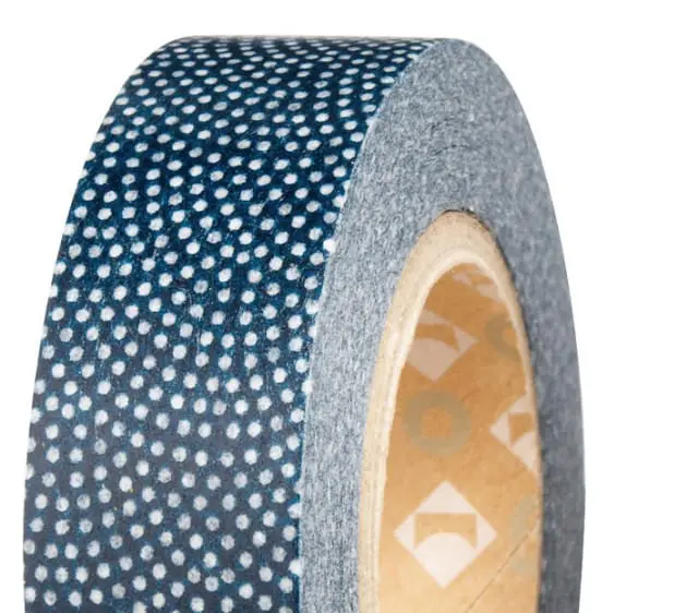 Close-up of a roll of dark blue washi tape with a white polka dot pattern.