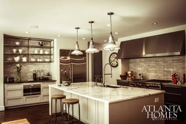 Modern kitchen with a large marble island, stainless steel appliances, subway tile backsplash, and industrial pendant lights.