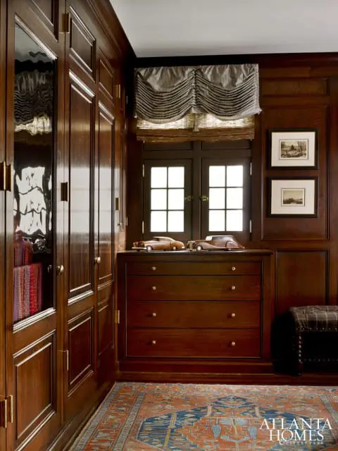Dark wood paneled room with built-in closets, a dresser with model cars, and a patterned rug.