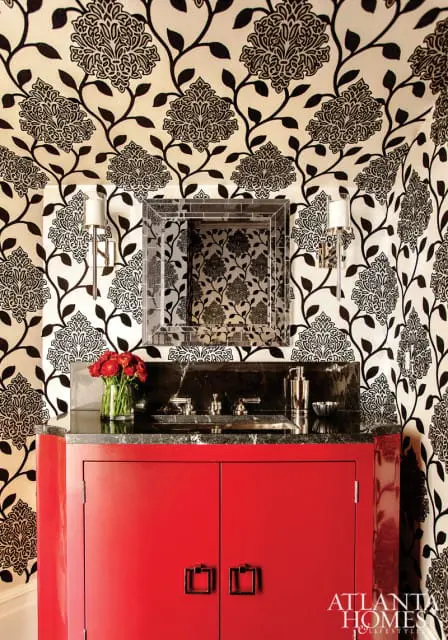 Powder room with bold black and white floral wallpaper, a red lacquered vanity with nickel hardware, and a black granite countertop with a vessel sink and chrome fixtures.