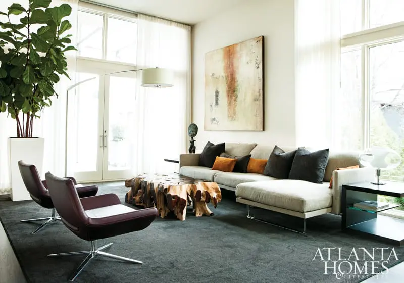 Living room with a sectional sofa, two burgundy leather chairs, a large abstract painting, and a live-edge wood coffee table.