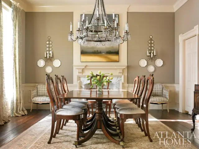 Dining room with dark wood table and chairs, crystal chandelier, fireplace, and textured taupe walls.