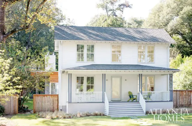White two-story house with a gray roof, white porch with gray columns, and a wooden fence in the yard.