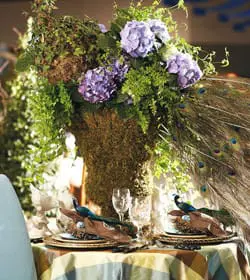 Table set with a plaid tablecloth, peacock feather accents, and a floral centerpiece with hydrangeas.