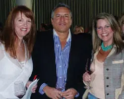 Two women and one man smiling at the camera. The woman on the left wears a white top, the man wears a blue striped shirt and black jacket, and the woman on the right wears a tan jacket and turquoise necklace.