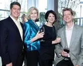 Four adults posing for a photo, two men and two women, holding wine glasses.